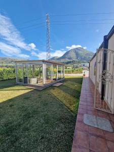 Private villa relax 2 &spa في Borgetto: منزل زجاجي على حديقة مع جبال في الخلفية