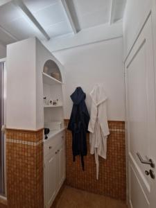 Private villa relax 2 &spa في Borgetto: مطبخ مع خزائن بيضاء وملابس سوداء معلقة