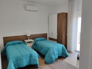 two beds in a bedroom with blue comforter at Casa Mikaela sea view in Vieste
