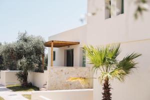 a white house with a palm tree in front of it at Magnolia Villas Potos Thassos in Potos