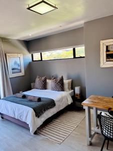 a bedroom with a bed and a table and windows at Lower Point Surf Studio in Jeffreys Bay