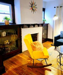 a living room with a yellow chair and a fireplace at Lovely! near Cleve Clinic/UH/CWRU/Dwntwn w/porch in Cleveland
