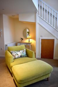 un divano giallo in soggiorno con scala di WEE SUZIE STAYS - Stunning George St Apartment a Perth