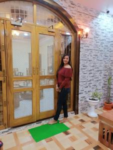 a woman standing on a green mat in front of a door at Adbhut Nivas (Home Stay) in Bhopal