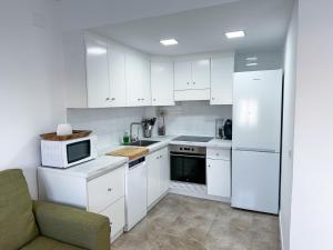 cocina blanca con electrodomésticos blancos y sofá en Casa ”Playa”, en Santa Pola