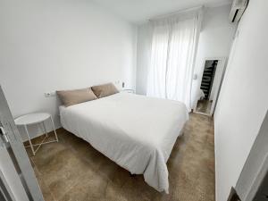 a white bedroom with a white bed and a window at Casa ”Playa” in Santa Pola