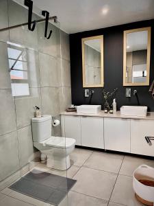 a bathroom with a white toilet and two sinks at Lower Point Surf Studio in Jeffreys Bay