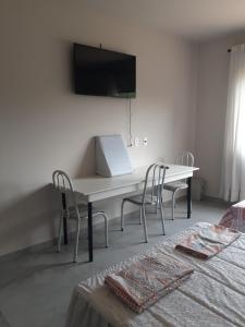 einen weißen Tisch und Stühle in einem Zimmer mit einem Bett in der Unterkunft Suítes Flor do Maracujá 02 in Ponta Grossa