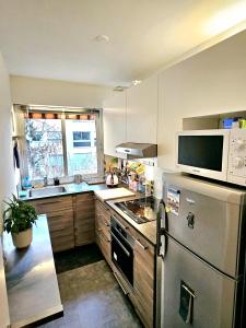 een keuken met een roestvrijstalen koelkast en een magnetron bij Beautiful & cosy apartment - La Défense in Courbevoie