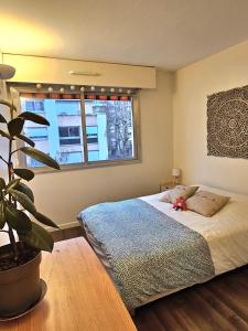 een slaapkamer met een bed en een potplant bij Beautiful & cosy apartment - La Défense in Courbevoie