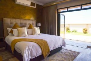 a bedroom with a large bed and a large window at Menucha Country Lodge in Mthatha