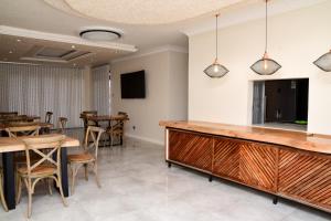 a dining room with a bar and tables and chairs at Menucha Country Lodge in Mthatha