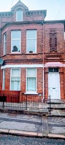 a brick building with white doors on a street at Aaron's Holiday Home in Belfast