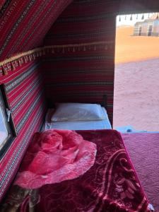 Una cama en una tienda con una manta roja. en Khaled's Camp, en Wadi Rum