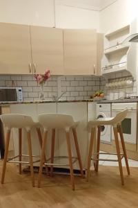 uma cozinha com armários brancos e uma mesa e cadeiras em Aaron's Holiday Home em Belfast