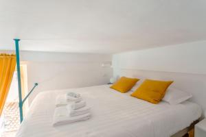 uma cama branca com almofadas amarelas e toalhas em Babuino Mini Loft em Roma