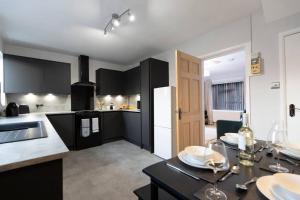 uma cozinha com armários pretos e uma mesa com pratos em Carrick House em Hartlepool