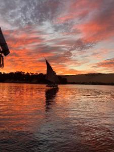 a boat with a sail in the water at sunset at Nile View Guest House in Aswan