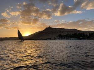 una barca a vela in acqua con una montagna sullo sfondo di Nile View Guest House a Aswan