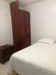 a bedroom with a bed and a wooden cabinet at Apartamento segundo piso B in Santa Cruz de Barahona