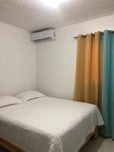 1 dormitorio con cama y cortina en Apartamento segundo piso B en Santa Cruz de Barahona