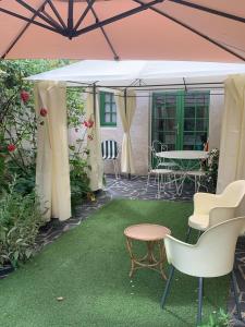 un patio con tavolo e sedie sotto una tenda. di Capucine a Noyen-sur-Sarthe