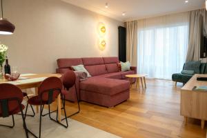 a living room with a red couch and a table at Raspberry apartment and SPA in Dziwnów