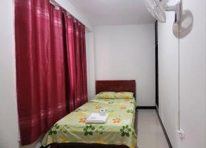 een klein bed in een kamer met een rood gordijn bij Hospedaje Vista Paraíso in Tingo María
