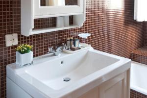 a bathroom with a white sink and a red tiled wall at Hotel Apartamento Solverde in Espinho