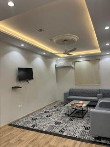a living room with a couch and a screen and a table at هابي دريم للشقق المخدومة in Ukaz