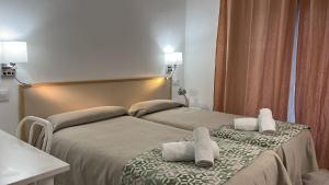 two beds in a hotel room with towels on them at Hostal Alhambra Tarragona in Tarragona