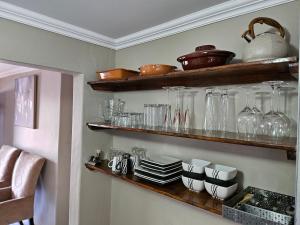 a kitchen with wooden shelves with glasses and utensils at TheeHost@1924 in Mmabatho