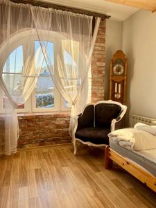a bedroom with a chair and a window and a clock at Apartament Zimowa Cisza in Piwniczna-Zdrój