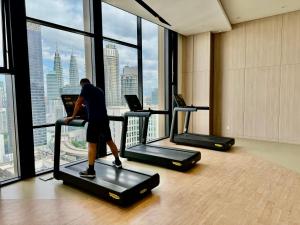 un homme sur un tapis de course dans une salle de sport donnant sur la fenêtre dans l'établissement Axon Residence By Classy 1 minutes Pavilion, à Kuala Lumpur