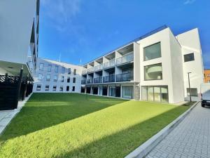 a large white building with a green lawn in front of it at Lulu Apartments - Apartament FLORA z klimatyzacją - Solny Resort in Kołobrzeg