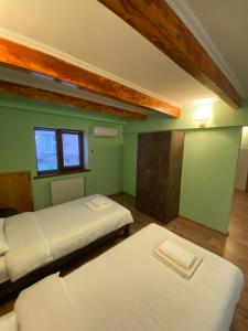 two beds in a room with green walls and a window at Nagi House in Zugdidi