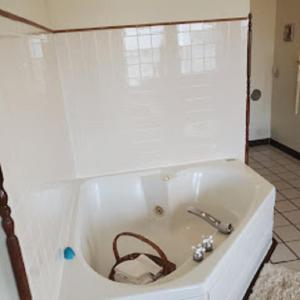 eine weiße Badewanne mit braunem Gürtel im Bad in der Unterkunft Karsten Hotel in Kewaunee