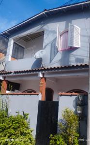 een wit huis met twee ramen en een hek bij Casa praia para temporada Parque Mambucaba Angra in Angra dos Reis
