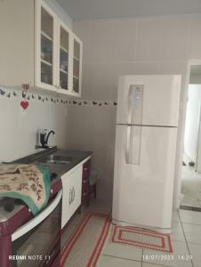 a kitchen with a white refrigerator and a sink at Casa praia para temporada Parque Mambucaba Angra in Angra dos Reis