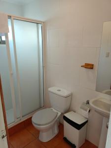 a white bathroom with a toilet and a sink at Hostal Quiriyuca Sur in Horcón