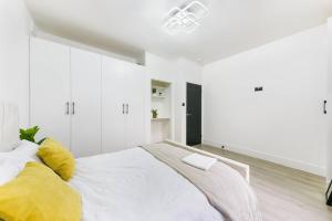 a white bedroom with a large bed with yellow pillows at Modern London Apartment with WIFI in Norwood