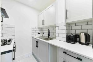 eine weiße Küche mit weißen Schränken und einem Waschbecken in der Unterkunft Modern London Apartment with WIFI in Norwood