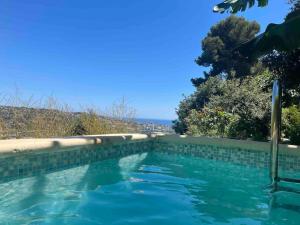 - une piscine d'eau bleue à côté d'un mur dans l'établissement Charmant appart 35m² dans villa, à Saint-Laurent-du-Var