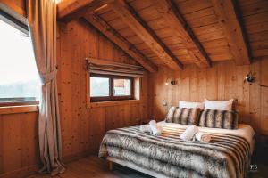 ein Schlafzimmer mit einem Bett in einem Holzzimmer in der Unterkunft Chalet Mont Blanc - Conciergerie de la Yaute in Cordon
