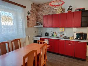 a kitchen with red cabinets and a wooden table at Apartmány u koní 