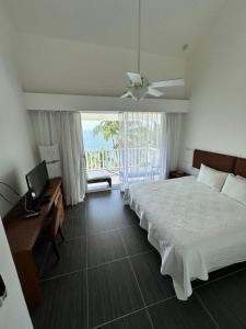 a bedroom with a bed and a desk and a television at Vista Mare Ocean View Top Floor Condo, Samana in Santa Bárbara de Samaná