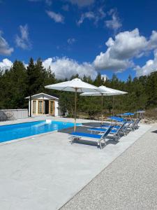 a group of chairs and umbrellas next to a swimming pool at Villa VitvikenA in Gotland Pool in Slite