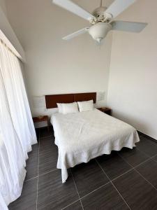 a bedroom with a white bed with a ceiling fan at Vista Mare Ocean View Top Floor Condo, Samana in Santa Bárbara de Samaná