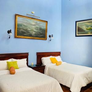 2 camas en una habitación con paredes azules en Hotel Antigua Casa de Piedra en San Miguel de Allende
