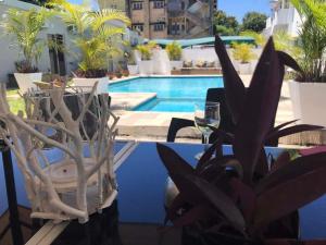 a table with a glass of wine next to a pool at Guesthouse MALAGUETA INN II in Maputo